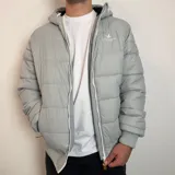 Campera inflada negra con capucha, cierre frontal blanco y puños elásticos acanalados. Presenta el logo de la marca Santa Barbara Outfitters bordado en el pecho.