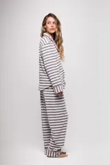 Pijama de tela tipo velvet a rayas horizontales grises y blancas, con vivos en color rojo. Incluye camisa de manga larga con botones frontales y bolsillo en el pecho, y pantalón recto con elástico en la cintura.