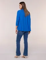 Cárdigan blanco de manga tres cuartos, con diseño abierto en estilo cascada y ruedo irregular.