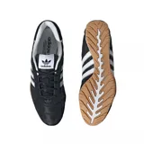 Championes adidas modelo Adi Racer Lo, de diseño inspirado en el automovilismo. Presentan una capellada de color negro con costuras acolchadas en forma de diamante, las icónicas tres tiras laterales en blanco y suela de goma color caramelo con detalle de logo en el arco.