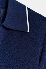 Top de punto confeccionado en mezcla de viscosa, color azul marino, de manga corta y cuello polo con solapas y escote en V. Presenta detalles de vivos a contraste en color blanco en el cuello, las mangas y el bajo.