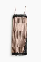 Vestido midi de satén color beige con estampado de lunares negros, breteles finos ajustables, escote recto con ribete de encaje negro, tajo lateral con detalle de encaje y bajo con terminación de encaje.
