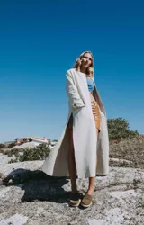 Tapado marrón de cuero con corte a la rodilla, mangas largas y aberturas laterales.