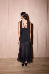 Vestido largo negro confeccionado en crepé y gasa, de corte al cuerpo con escote recto, tiritas finas y falda larga semitransparente con tajo lateral pronunciado. Incluye accesorio tipo corbatín a juego.