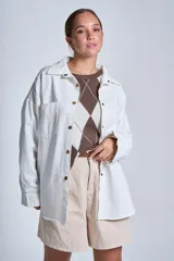 Sobrecamisa blanca de gabardina con cuello camisero, cierre frontal con botones dorados, bolsillos de parche en el pecho y corte holgado.