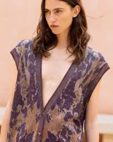 Chaleco oversize de punto con hilo lúrex, cuello en V y cierre frontal de botones. Presenta un estampado jacquard con efecto marmolado en tonos marrones y morados, bolsillos frontales aplicados y ribetes en contraste en el escote, sisas y dobladillo.