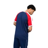 Remera deportiva Umbro del Club Nacional de Football, color azul con mangas en rojo y cuello redondo blanco. Presenta el logo de la marca y el escudo del club bordados en el pecho.