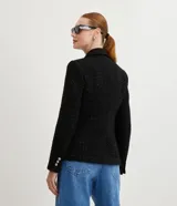 Blazer negro de tweed con hilos metalizados, corte entallado, escote en V profundo, bolsillos delanteros con solapa y doble botonadura con seis botones decorativos de strass.