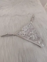Microtanga de encaje con diseño floral, breteles finos regulables y terminaciones en color tostado.