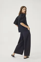 Pantalón culotte negro de lino orgánico, con cintura alta, diseño plisado y bolsillos laterales.