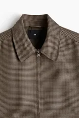 Campera con cuello, cierre oculto frontal, bolsillos insertados delanteros y bolsillo interior. Mangas largas con puños abotonados y trabilla ajustable con botón en los laterales del bajo.