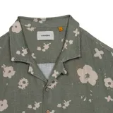 Camisa manga corta verde militar con estampado floral claro, cuello cubano y cierre frontal con botones.