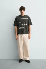 Camiseta de algodón con corte relajado, cuello redondo y manga corta. Presenta estampados gráficos a contraste en el frente con inscripciones tipo señalética.