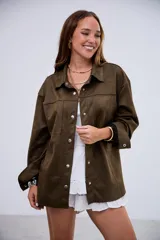 Sobrecamisa de gamuza en color verde militar, con corte oversize, cuello clásico, cierre frontal con botones metálicos y bolsillos frontales tipo parche.