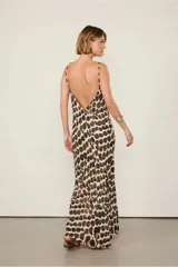 Vestido largo con estampado de manchas marrones sobre fondo beige, escote halter con tirantes finos y detalle de cuentas, calce suelto y largo midi.