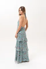 Vestido largo celeste con estampado abstracto en tonos marrones, escote halter con abertura en el frente y volados escalonados en la falda.