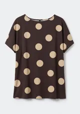 Blusa de manga corta con cuello redondo, confeccionada en tela oscura con estampado de lunares grandes en color beige.