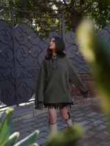 Buzo color crudo con cuello de piel sintética color crema, abertura parcial con cierre de cuero marrón y hebilla dorada, puños con ajuste de cuero marrón y bolsillos laterales.