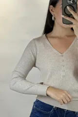 Buzo de hilo gris con textura acanalada, escote en V y cierre frontal con botones pequeños.