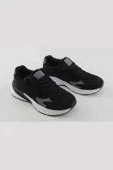 Championes deportivos de estilo urbano, color negro con detalles en gris y suela blanca. Presentan un diseño con cordones y paneles superpuestos.