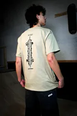 Remera de corte holgado color verde militar, con cuello redondo y mangas cortas. Presenta un pequeño estampado negro en el pecho y un diseño gráfico vertical en la espalda con tipografía y el texto "by riders for riders".