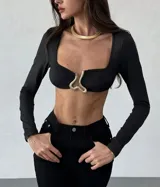 Top negro de mangas largas con escote cuadrado y abertura en el pecho con detalle metálico dorado.