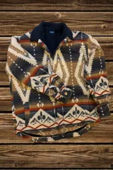Campera con estampado azteca en tonos azul, marrón y beige, con cuello polo y cierre parcial con cremallera.