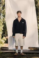 Buzo tipo polo de manga larga, color negro, con cuello y cierre parcial frontal. Presenta un pequeño bordado en el frente y la espalda.