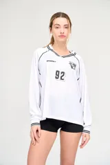 Camiseta blanca de manga larga con cuello en V y detalles en negro. Presenta el logo de la marca en el pecho, el número 92 y un escudo con tres balones de fútbol.