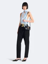 Bolso mini Balmain modelo B-Buzz, color negro, con asa superior rígida y correa de hombro extraíble. Presenta solapa con cierre de broche a presión y aplique metálico dorado con el logo de la marca.