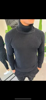 Buzo de hilo negro con cuello alto y mangas largas.