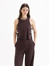 Top de twill color beige, de silueta recta y diseño sin mangas con cuello redondo. Se destaca por sus aberturas laterales con lazos regulables y remaches metálicos.