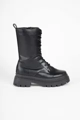 Borcego negro de caña media en símil cuero, con interior acolchonado, cordones a tono, cierre en uno de sus laterales y plataforma tipo tractor de 6cm de alto.