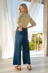 Blusa cruzada con estampado floral en tonos de lila, amarillo y verde. El cruce se ajusta a la cintura con un lazo. Tiene mangas 3/4 con puños elásticos y escote en V.