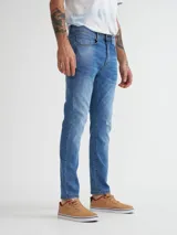 Pantalón de jean celeste de corte slim fit con efecto lavado y roturas sutiles.