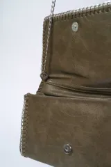 Cartera de hombro con solapa y bordes ribeteados con una cadena metálica entrelazada. Presenta un diseño tipo sobre con acabado texturizado y una correa de cadena larga.