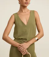 Blusa sin mangas de tejido tipo airflow, con escote en V y breteles anchos. Presenta una textura ligeramente arrugada y costura central vertical decorativa.