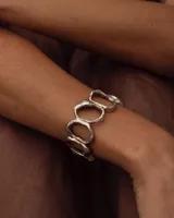 Brazalete rígido de diseño orgánico, compuesto por eslabones irregulares unidos entre sí, con acabado metálico brillante.