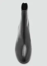 Botin de cuero vacuno color negro, con taco bloque de 5,5 cm, punta redonda y cierre de cremallera en la parte posterior.