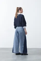 Jean de calce ultra wide confeccionado en denim de algodón color negro. Presenta una silueta amplia desde la cadera y un panel lateral en contraste que estiliza la pierna.