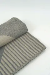 Bufanda de tejido de punto en tonos marrón y tostado, con diseño geométrico y flecos en los extremos.