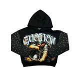 Hoodie negro de corte boxy fit, con capucha y mangas largas decoradas con pedrería brillante. Cuenta con un gran estampado frontal que muestra un querubín con los ojos vendados tensando un arco, acompañado de la palabra 'EMOTION' en tipografía gótica.