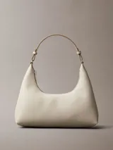 Cartera de hombro Calvin Klein de diseño estructurado en color beige, con cierre de cremallera superior, correa ajustable y detalle del logo de la marca grabado en la parte frontal.