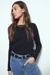 Remera de manga larga con ajuste al cuerpo, confeccionada en tejido acanalado de color marrón. Presenta cuello redondo y terminaciones con borde ondulado en puños y ruedo.