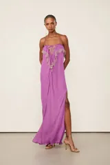 Vestido largo lila de viscosa con tirantes finos, escote recto con lazo ajustable, silueta fluida, tajo lateral en la falda y detalles de encaje en el canesú del busto.