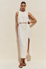 Sandalia plana de cuero color marrón oscuro (bordó/caoba) con tira en T y hebilla ajustable en el tobillo. Presenta un aplique decorativo curvo en tono ámbar/marrón rojizo con borde dorado en la tira del empeine.