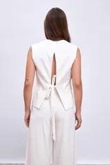 Chaleco blanco con cuello en V y cierre frontal con botones.