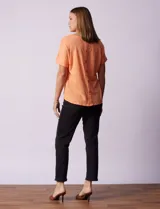 Remera blanca texturada con cuello redondo y mangas cortas con dobladillo. Detalle de botones en la espalda.