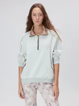 Buzo de algodón con cuello alto y cierre frontal parcial. Presenta bolsillos laterales con cierre y cuello con interior en contraste. Diseño de corte oversize.