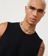 Musculosa básica para hombre de corte recto y cuello redondo, confeccionada en tejido de algodón. Presenta un diseño liso con un pequeño tag decorativo en el bajo.